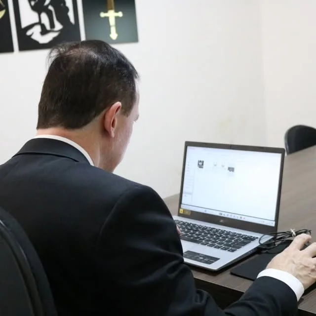 Dr. Eduardo Chimenes de costas, trabalhando no computador do escritório