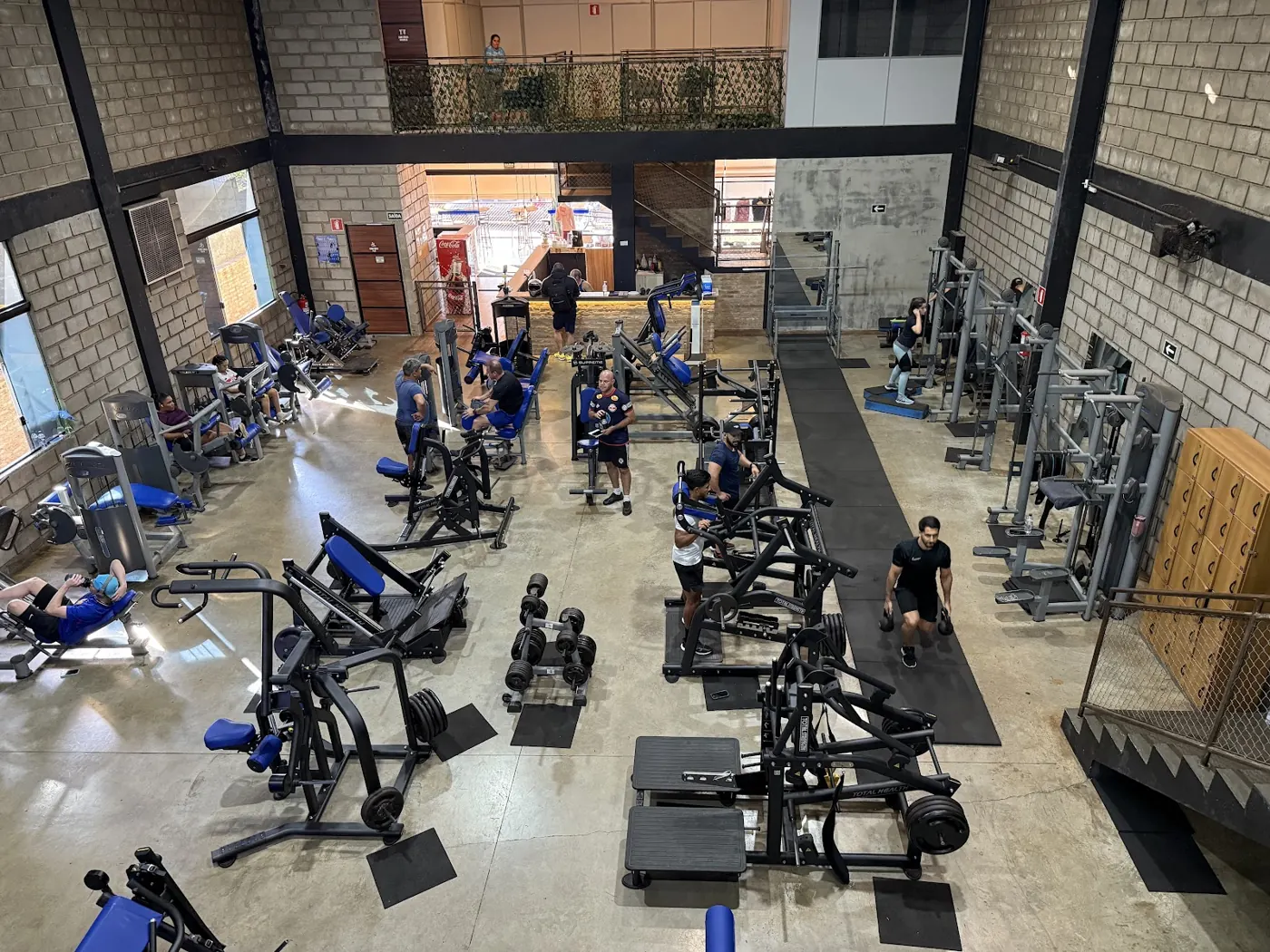 Vista de cima da sala de musculação, com dezenas de aparelhos e alunos treinando